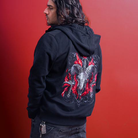 Someone with long dark hair wears the Baphomet Unisex Embroidered Hoodie, featuring a ram’s skull with curled horns and red flaming accents on the back, creating a gothic streetwear look against a vivid red background.