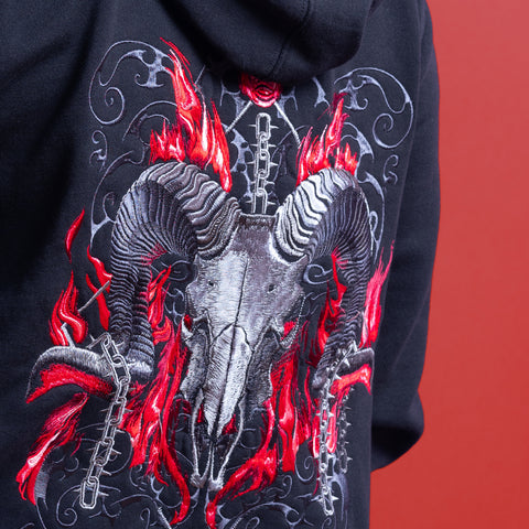 The Baphomet Unisex Embroidered Hoodie features a black design with a ram skull, red flames, silver chains, and swirling accents for bold gothic streetwear—perfect for metal fashion fans. Displayed on a vivid reddish background.