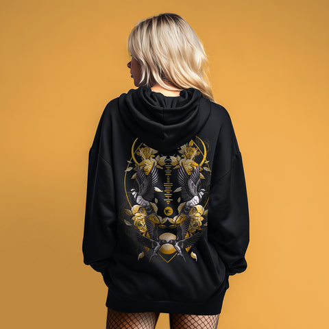 Someone with long blonde hair models the Custom Song Code Unisex Embroidered Hoodie, a black zip-up with gold and white floral, bird, and geometric embroidery on the back, set against a solid yellow background.