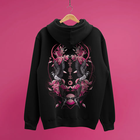 A Custom Song Code Unisex Embroidered Hoodie in black hangs on a wooden hanger against a pink background, showcasing an intricate pink and white embroidered design with koi fish, roses, leaves, and geometric shapes on the back.