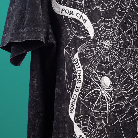 The Spider Web Embroidered Glow In The Dark Unisex T-shirt features a black base with a white spider web and spider, plus a ribbon reading "FOR THE SPIDER IS CHAOS." Its glow-in-the-dark design makes it a perfect bold Halloween gift.
