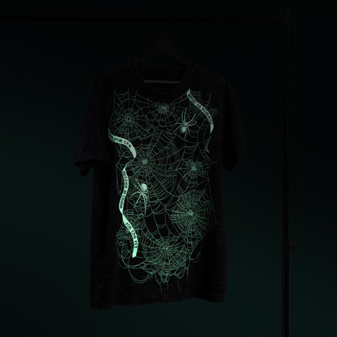 The Spider Web Embroidered Glow In The Dark Unisex T-shirt features a vibrant green spiderweb and spiders on black fabric, glowing brilliantly in the dark—an eye-catching choice and perfect Halloween gift.