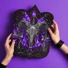 A person holds the Baphomet Embroidered Back Patch: a black accessory showcasing a ram skull with large curved horns, purple flames, and ornate patterns—ideal for fans of occult fashion or striking Baphomet aesthetics.