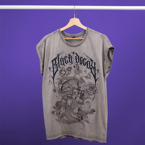 The Black Decay Embroidered Female T-shirt features a gray acid-wash look with an intricate black skull, rose, and snake graphic, plus stylized text, displayed on a wooden hanger against a solid purple background.