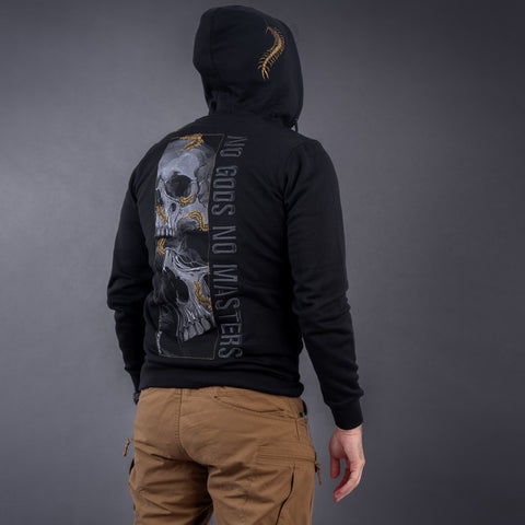 Wearing the Skull & Scolopendras Limited Edition Embroidered Hoodie with a skull and "NO GODS NO MASTERS" on the back, paired with tan pants, a person stands facing away against a gray background.