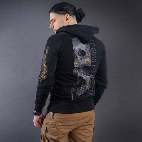 A man with dark hair in a ponytail models the Skull & Scolopendras Limited Edition Embroidered Hoodie with a bold skull and spine design plus "NO GODS, NO MASTERS" on the back, paired with tan pants against a gray background.