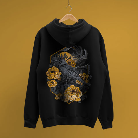 The Crow And Peonies Unisex Embroidered Hoodie, in black, hangs on a wooden hanger before a mustard yellow background, showcasing a detailed crow with yellow flowers and dark foliage embroidered on the back.