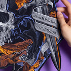 A hand displays the Skull and Dagger Embroidered Back Patch, featuring autumn leaves and a dagger with "DEATH BEFORE DISHONOR," ideal for gothic fashion fans, set against a purple background.