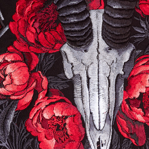 The Blesbok Skull and Flowers Embroidered Patch features a silver ram skull with black horns, vivid red flowers, and green leaves on dark fabric—ideal as a goth fashion back patch or bold dark art accessory.