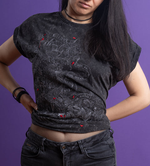 Wearing the Japanese Koi Fish Embroidered Female T-shirt with black cotton fabric and red accents, a person stands against a purple backdrop, lifts the shirt to show fishnet underneath, and pairs it with rolled sleeves and dark jeans for an edgy look.