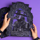 Two hands hold the Plague Doctor Embroidered Back Patch, featuring a plague doctor in a beaked mask and hat with an ornate border on a bold purple background—a striking Victorian-inspired cosplay accessory.